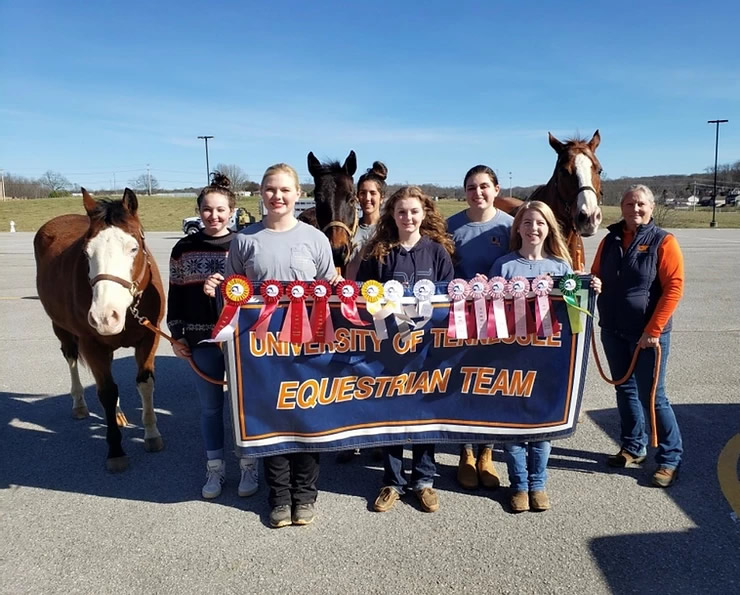 Equestrian team members posing with ribbons and horses